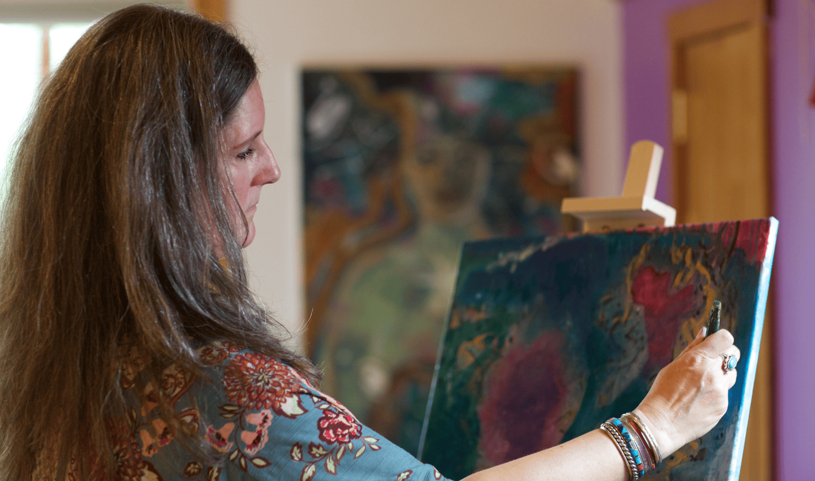 Profile of Intentional Creativity facilitator Erika Primozich of Boulder, CO painting on a canvas.
