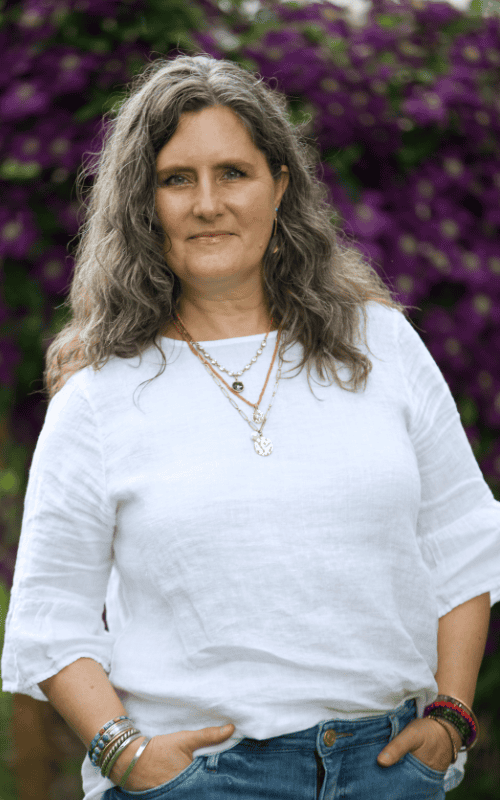 Intentional Creativity facilitator Erika Primozich smiles into the camera with her hands in her pockets in Boulder, CO